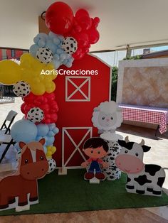 some farm animals and balloons in front of a red barn