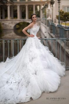 a woman in a white wedding dress standing on a balcony with her hands on her hips