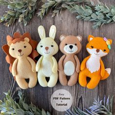 four stuffed animals sitting next to each other on a wooden surface with greenery around them