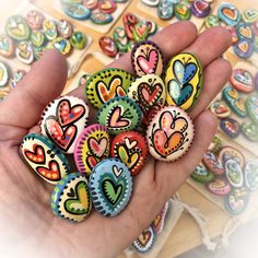 a hand holding lots of colorful heart shaped magnets