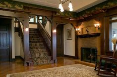 an empty living room with wood trimming and carpeted stairs leading up to the second floor