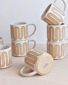 four coffee mugs are stacked on top of each other, one is made out of clay