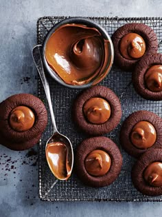 chocolate cupcakes with peanut butter frosting on a cooling rack next to a spoon