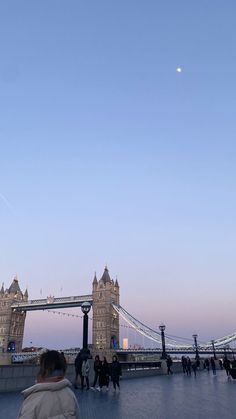 people are walking on the walkway near tower bridge