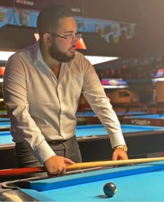 a man is playing pool in a bowling alley with his racket leaning on the table