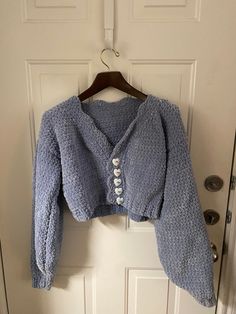 a blue sweater hanging on a door with buttons attached to the front and back of it