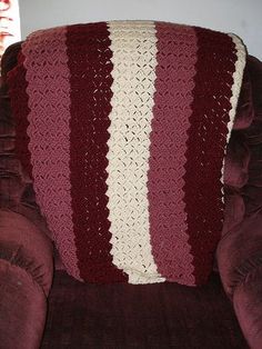 a crocheted blanket sitting on top of a chair next to a red couch