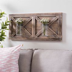 two mason jars with baby's breath in them are mounted on the wall above a couch