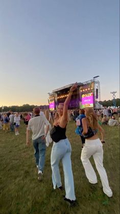 some people are dancing in the grass at a music festival with an onlooker