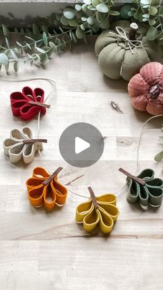 several different types of felt flowers on a white surface with greenery in the background