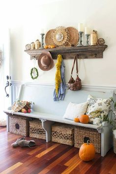 a bench with baskets and hats on it in front of a wall mounted coat rack