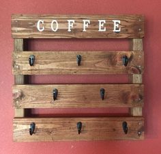 a coffee sign mounted to the side of a wall next to hooks on a red wall