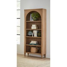 a wooden bookcase with books and plants on top of it in a living room