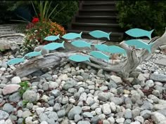 a group of fish sitting on top of rocks next to a tree trunk and stairs