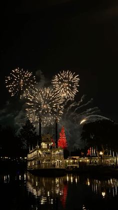 fireworks are lit up in the night sky above a lake and buildings with lights on them