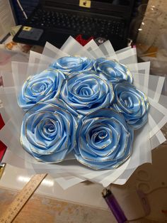 a bouquet of blue roses sitting on top of a white paper towel in front of a laptop computer