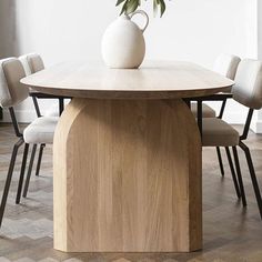 a wooden table with chairs around it and a white vase on top of the table