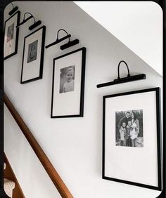 black and white photos hang on the wall next to an escalator in a home