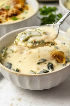 a spoon full of soup with spinach and cheese