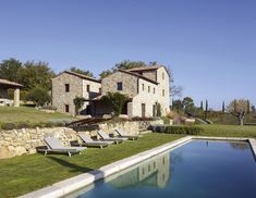 a house with a pool in front of it and lawn chairs next to the pool