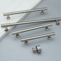 six stainless steel handles and knobs on a white surface