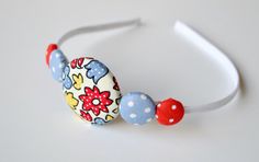 the headband is decorated with colorful fabric balls and polka dot dots on white background