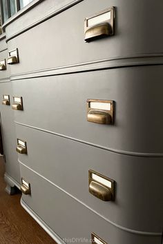 a gray dresser with brass handles and knobs