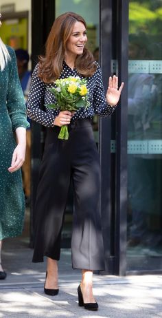 the duke and duchess of cambridge are walking down the street with flowers in their hands