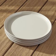 stack of white plates sitting on top of a wooden table