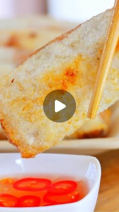 a piece of bread being dipped with toothpicks and dipping sauce in a bowl