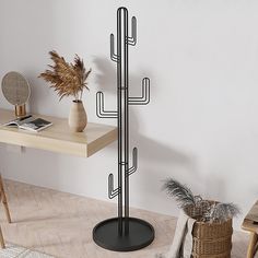 a tall metal cactus plant stands on a wooden floor in front of a white wall