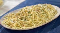 a plate of spaghetti with parmesan cheese on it and another dish in the background