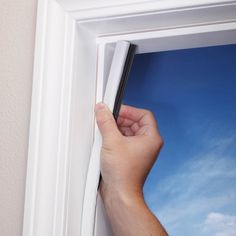 a hand is holding the edge of a white frame with a blue sky in the background