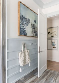 a white purse hanging on the wall next to a door with a painting above it