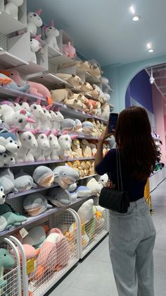 a woman taking a photo of stuffed animals in a store