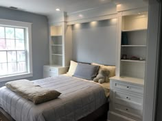 a bedroom with a bed, bookcases, and window in it's corner