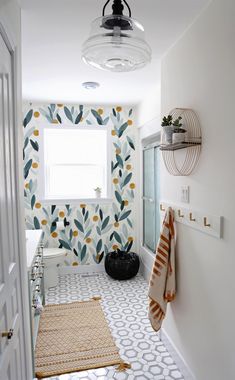 a white bathroom with yellow and blue wallpaper on the walls, rugs and lights above the bathtub