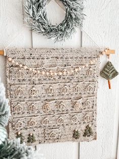 a crocheted wall hanging next to a christmas wreath