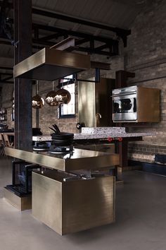 an industrial style kitchen with stainless steel appliances and counter tops, along with exposed brick walls