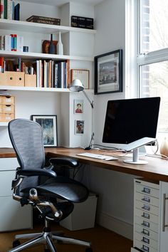 an office chair sits in front of a desk with a computer and bookshelf