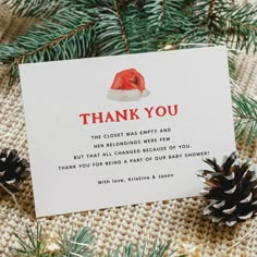 a thank card with a santa hat on it next to pine cones and evergreen branches