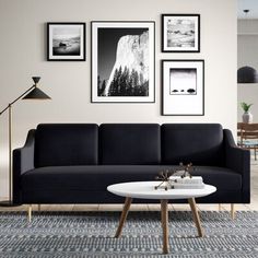 a living room with gray couches and pictures on the wall above it in black and white