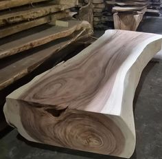 a wooden bench sitting on top of a floor next to stacks of wood planks