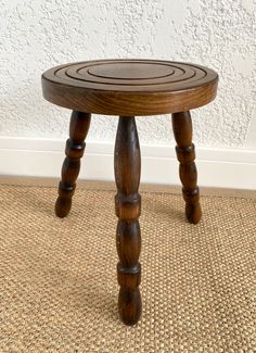 a small wooden stool sitting on top of a carpeted floor next to a wall