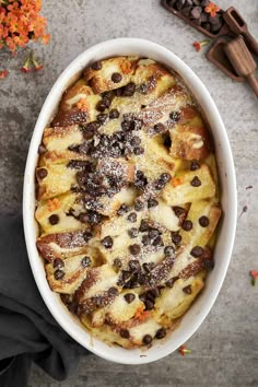 a casserole dish with chocolate chips and powdered sugar on top, surrounded by flowers