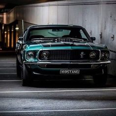 an old muscle car is parked in a parking lot next to a building at night