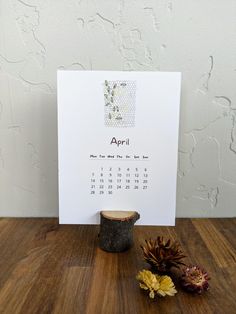 a calendar is sitting on a table next to some flowers and a potted plant