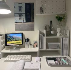 a desk with a computer monitor, keyboard and mouse next to some books on it