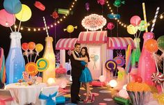 a man and woman standing in front of a candy shop with lots of candies