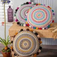 three crocheted baskets sitting on top of a wooden table next to a potted plant